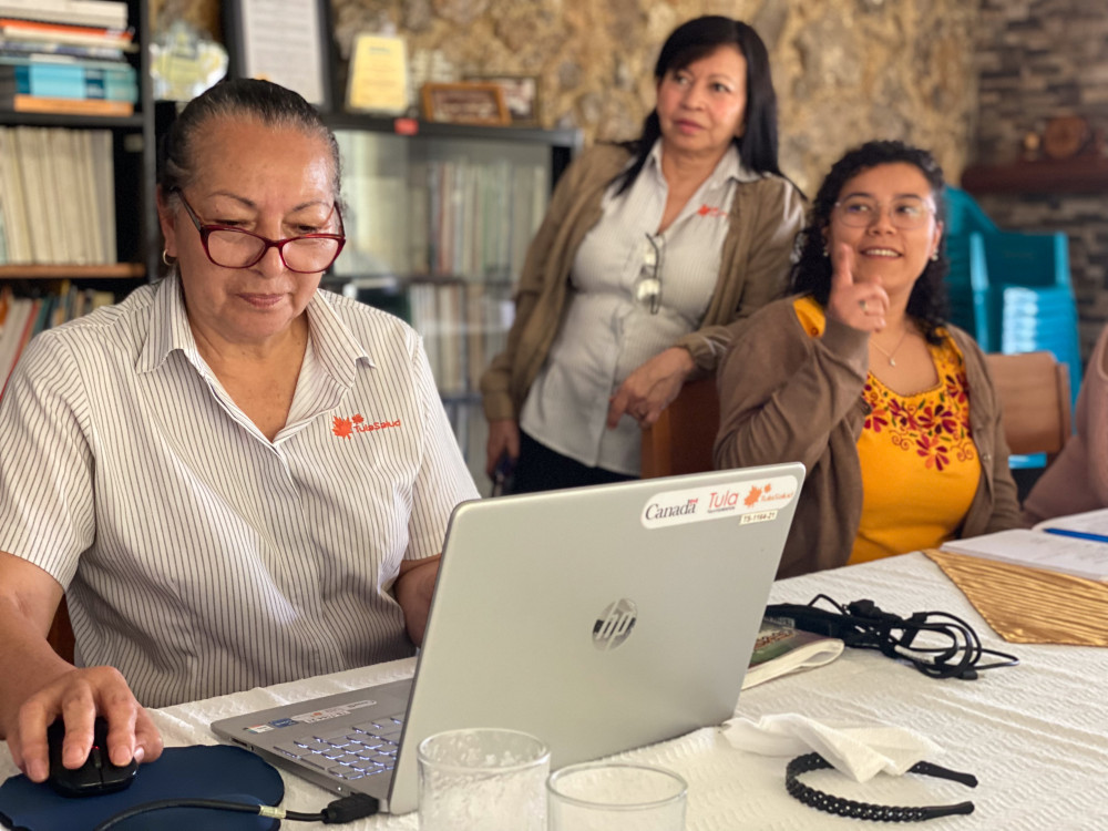 Tele-education manager Magdalena Juarez working on her laptop at the TulaSalud offices in Cobán, joined by Lobos, centre, and Gabriela Mancilla, a nursing instructor. Photo by Kristina Blanchflower